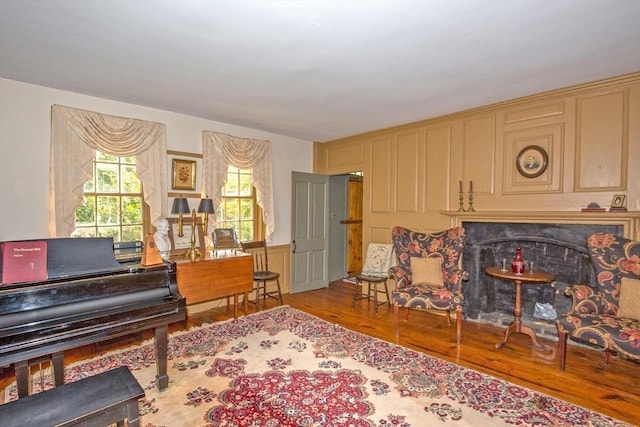 living area with a fireplace, a decorative wall, and wood finished floors