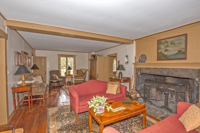 living area featuring a fireplace with flush hearth, beamed ceiling, and wood finished floors