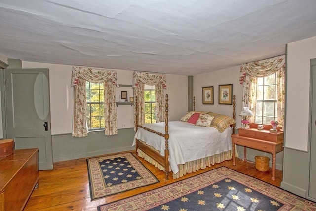 bedroom featuring baseboards, multiple windows, and wood finished floors