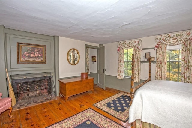 bedroom featuring baseboards, wood finished floors, and a fireplace