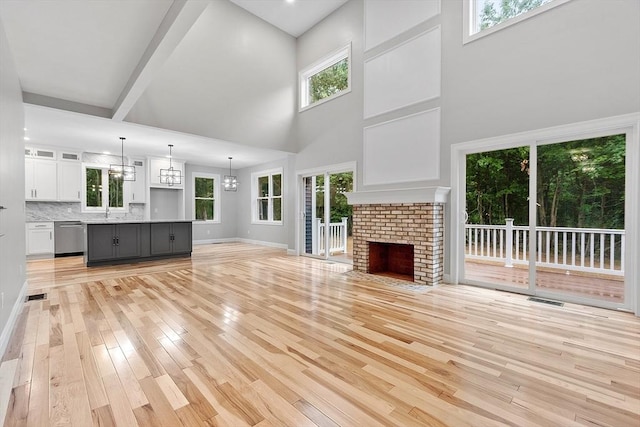 168 Justice Hill Rd Oakmont, Unit Oakmont, Sterling, MA 01564 - unfurnished living room with light wood finished floors, a sink, a high ceiling, a brick fireplace, and plenty of natural light