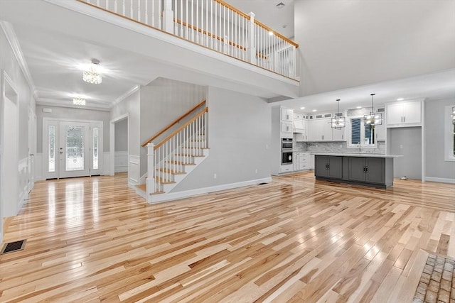 168 Justice Hill Rd Oakmont, Unit Oakmont, Sterling, MA 01564 - unfurnished living room with a chandelier, stairway, light wood finished floors, crown molding, and a high ceiling
