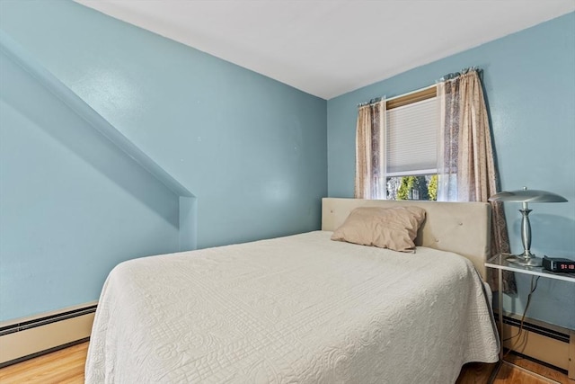 bedroom with baseboard heating and wood finished floors