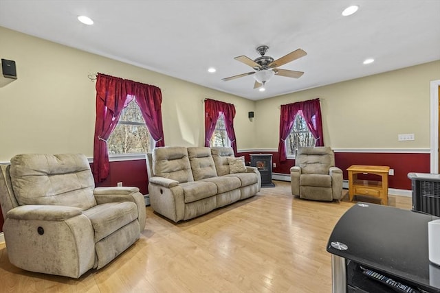 living room with a baseboard heating unit, recessed lighting, light wood-type flooring, and ceiling fan