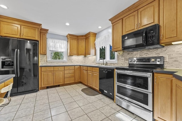 kitchen featuring light tile patterned floors, backsplash, black appliances, and a sink