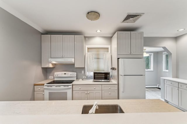 328 E Main St, Marlborough, MA 01752 - kitchen featuring white appliances, under cabinet range hood, a sink, light countertops, and a baseboard radiator