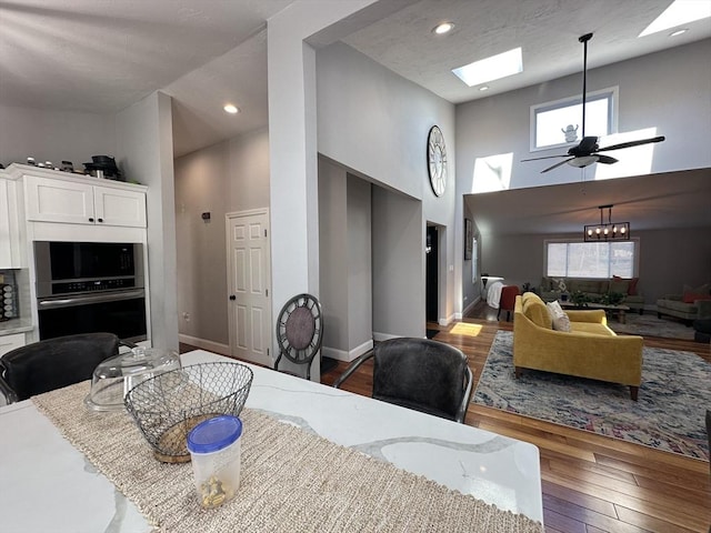 dining area featuring a high ceiling, dark hardwood / wood-style floors, and ceiling fan with notable chandelier