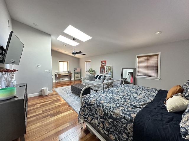 bedroom featuring lofted ceiling with skylight and light hardwood / wood-style flooring