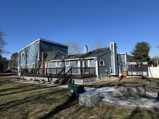 rear view of property with a fire pit, a deck, and a yard