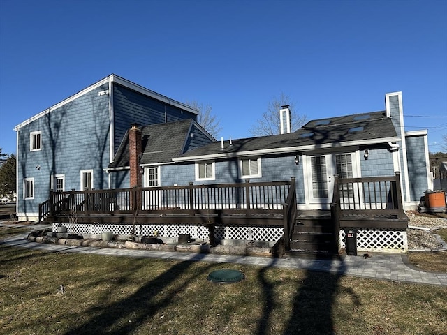 rear view of property featuring a lawn and a deck