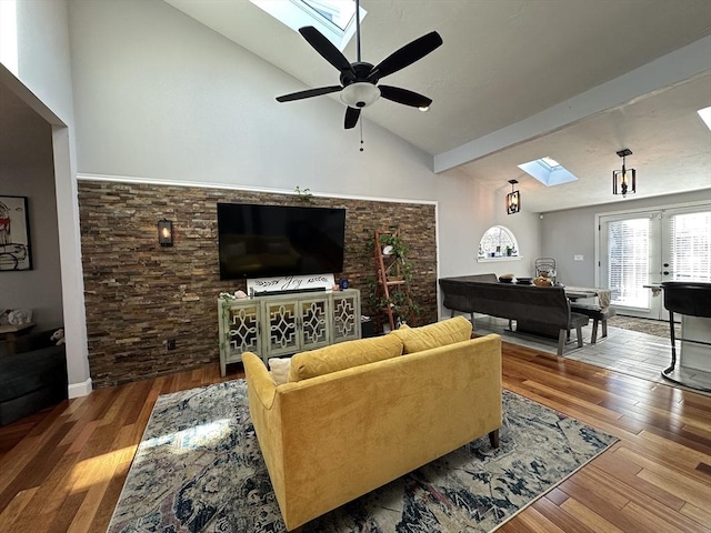 living room with french doors, hardwood / wood-style floors, ceiling fan, a skylight, and high vaulted ceiling