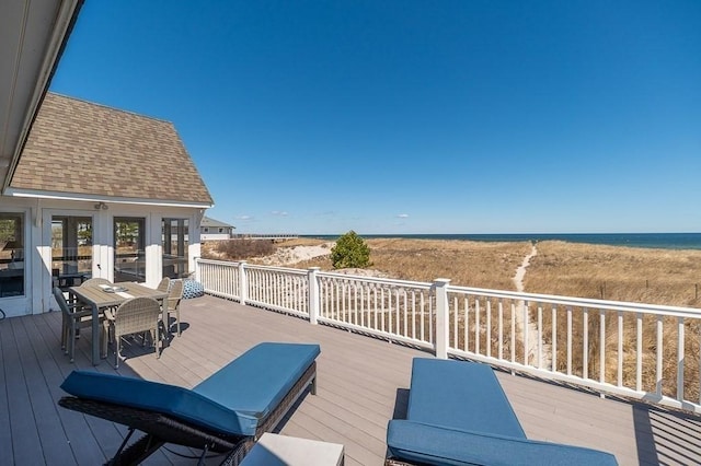deck with outdoor dining space, a water view, and french doors