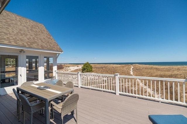 wooden terrace with a view of the beach, outdoor dining area, and a water view