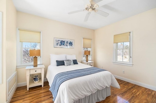 bedroom with baseboards, wood finished floors, ceiling fan, and multiple windows
