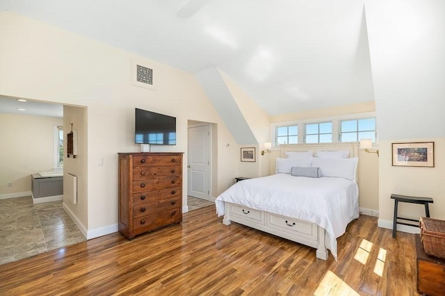 bedroom featuring baseboards, visible vents, wood finished floors, and vaulted ceiling
