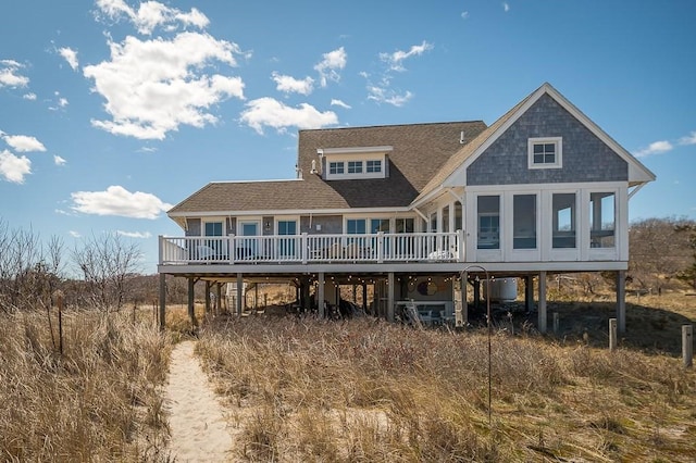 back of property featuring a wooden deck, a shingled roof, a carport, and a sunroom