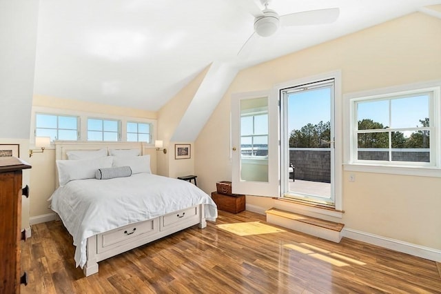bedroom featuring baseboards, wood finished floors, and lofted ceiling