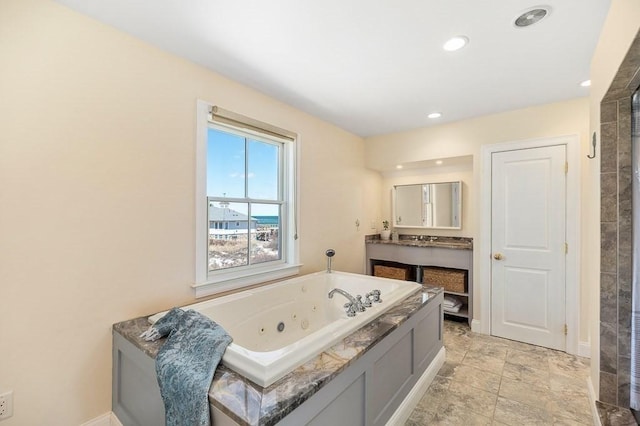 bathroom featuring baseboards, recessed lighting, vanity, and a jetted tub