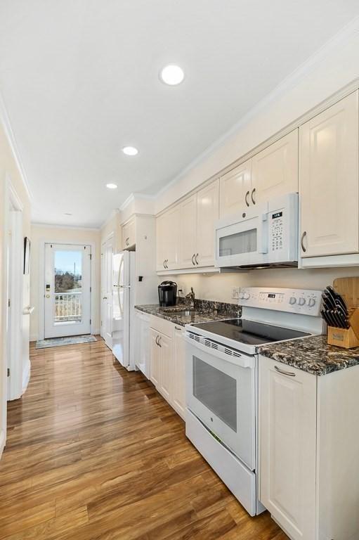 kitchen featuring white appliances, crown molding, and white cabinets