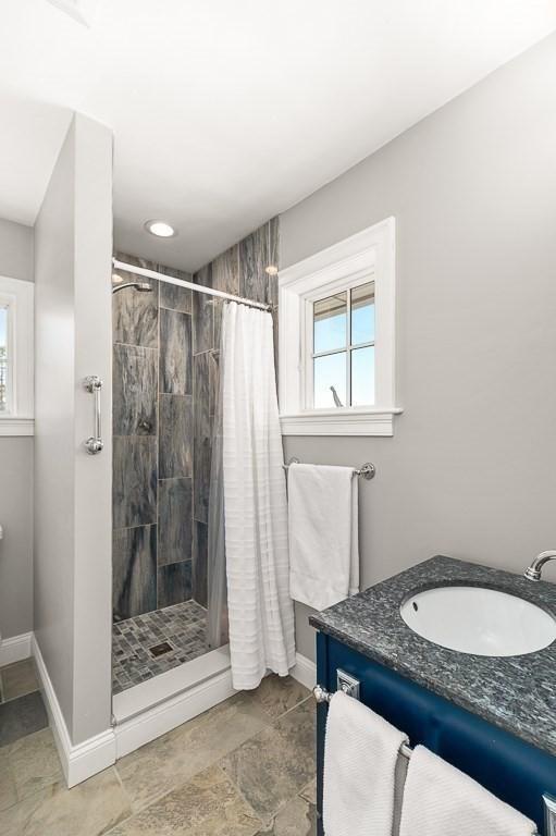 full bathroom featuring a stall shower, vanity, and baseboards