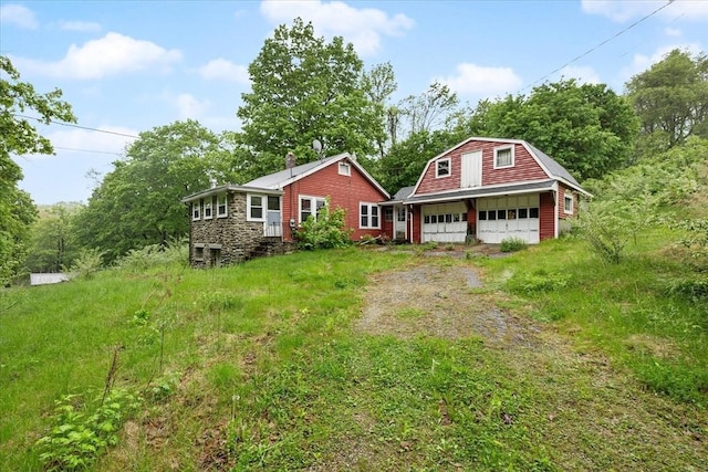 21 City Depot Rd, Charlton, MA 01507 - dutch colonial with an outdoor structure, a gambrel roof, a garage, dirt driveway, and stone siding