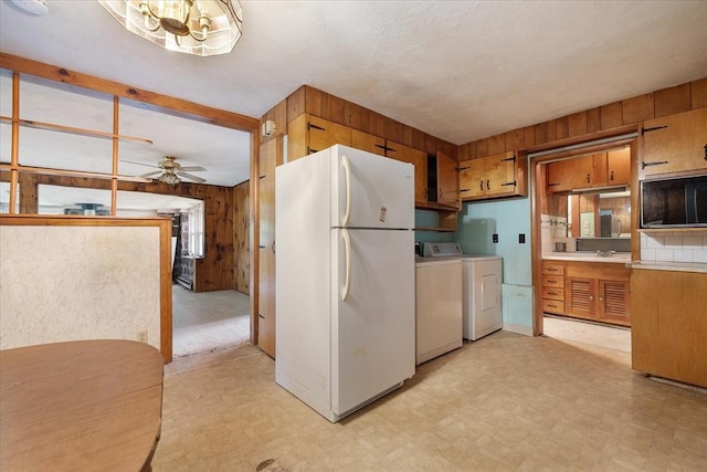 21 City Depot Rd, Charlton, MA 01507 - kitchen with freestanding refrigerator, wood walls, washing machine and dryer, light floors, and a chandelier
