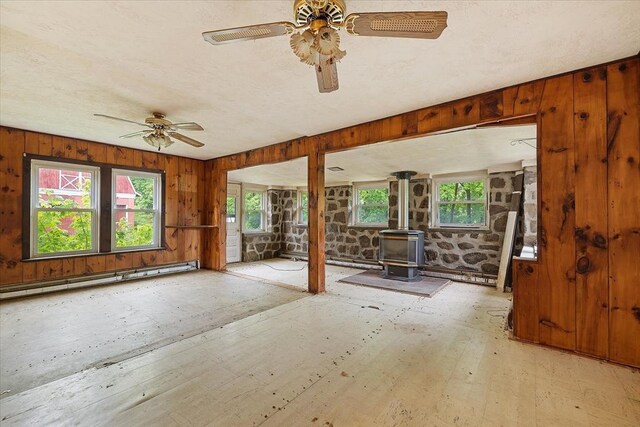 21 City Depot Rd, Charlton, MA 01507 - spare room with a wood stove, ceiling fan, wood walls, and a baseboard radiator