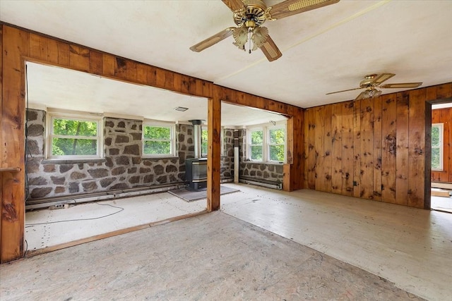 21 City Depot Rd, Charlton, MA 01507 - spare room featuring healthy amount of natural light, a wood stove, a ceiling fan, and wood walls