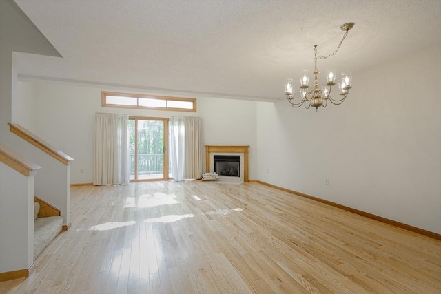 19 Spruce Pond Rd Unit 19, Franklin, MA 02038 - unfurnished living room featuring a chandelier, light wood finished floors, stairs, baseboards, and a fireplace