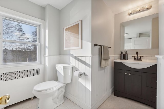 bathroom with radiator heating unit, toilet, tile patterned floors, and vanity