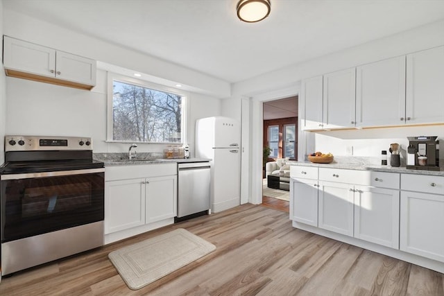 kitchen featuring white cabinets, light wood-type flooring, appliances with stainless steel finishes, and sink