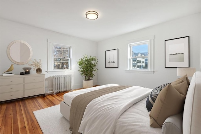 bedroom with radiator heating unit and light hardwood / wood-style flooring