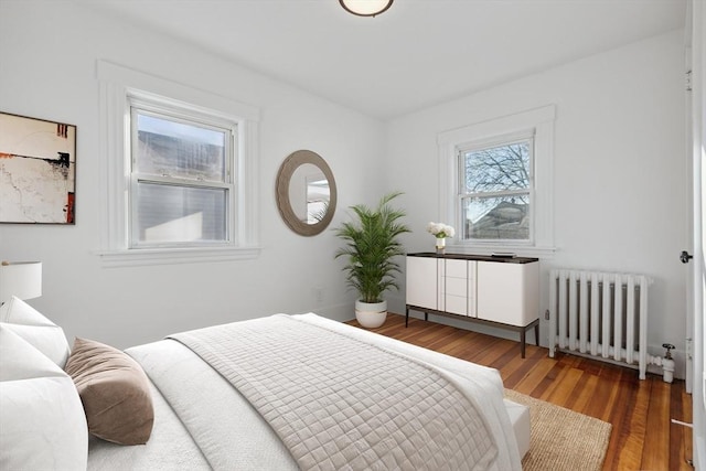 bedroom with radiator heating unit and dark hardwood / wood-style floors