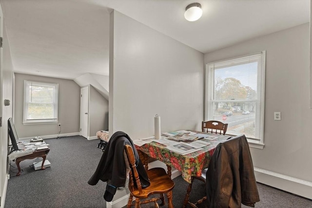 dining space featuring a healthy amount of sunlight, lofted ceiling, and dark colored carpet