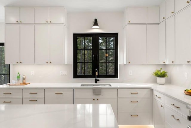 kitchen with a sink, decorative backsplash, white cabinetry, and light countertops