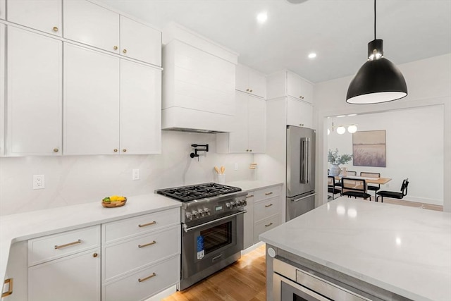 kitchen with light wood-style floors, high end appliances, white cabinets, and light countertops