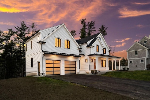 modern farmhouse style home with a lawn, driveway, a standing seam roof, an attached garage, and metal roof