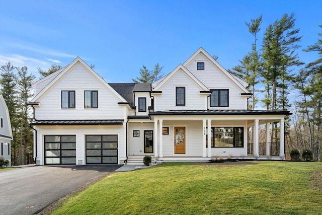 modern farmhouse with aphalt driveway, a garage, a front yard, and a standing seam roof