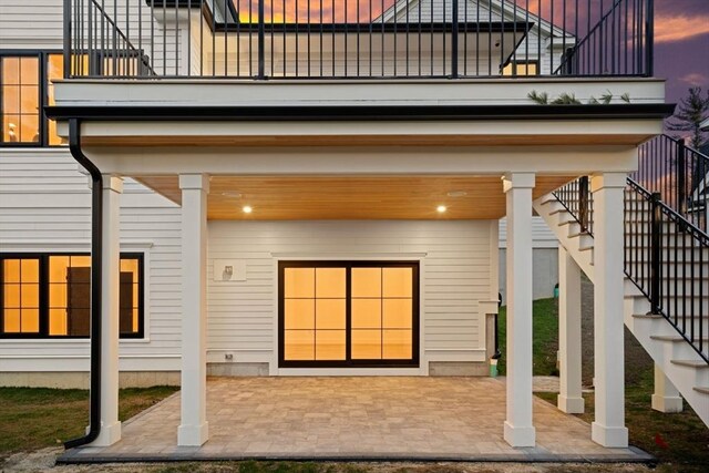 back of property featuring a patio, a balcony, and stairs