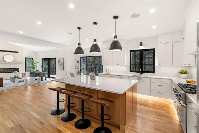 kitchen with a kitchen island, a breakfast bar, light countertops, white cabinets, and a sink