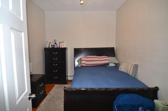 bedroom with a baseboard radiator and dark hardwood / wood-style floors