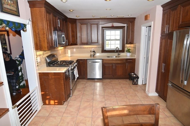 kitchen with sink, backsplash, light tile patterned floors, and appliances with stainless steel finishes