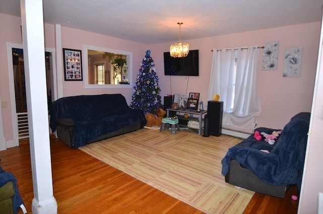 living room featuring a baseboard heating unit, hardwood / wood-style floors, and a notable chandelier