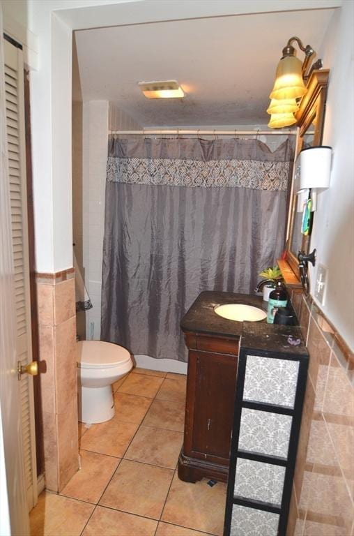 bathroom with toilet, tile patterned floors, a shower with curtain, tile walls, and vanity