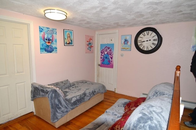 bedroom featuring a baseboard heating unit, a textured ceiling, and wood-type flooring