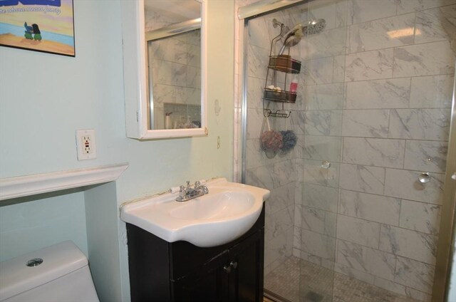 bathroom featuring toilet, an enclosed shower, and vanity