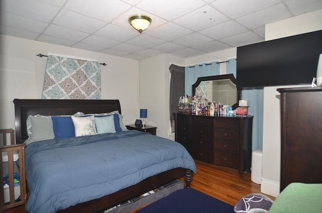 bedroom featuring a drop ceiling and hardwood / wood-style flooring