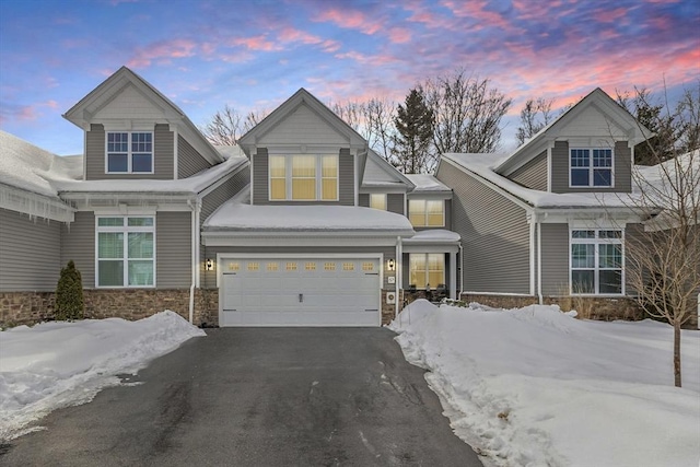 craftsman inspired home with driveway, stone siding, and an attached garage