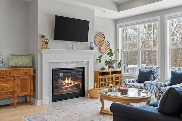 living area featuring visible vents, wood finished floors, a high end fireplace, and baseboards