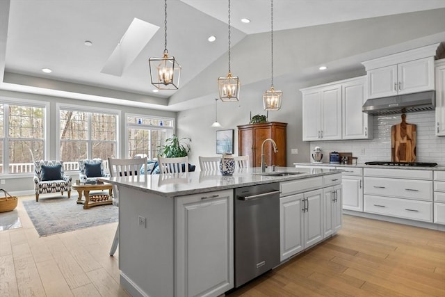 kitchen with light wood-type flooring, a kitchen island with sink, under cabinet range hood, and gas stovetop